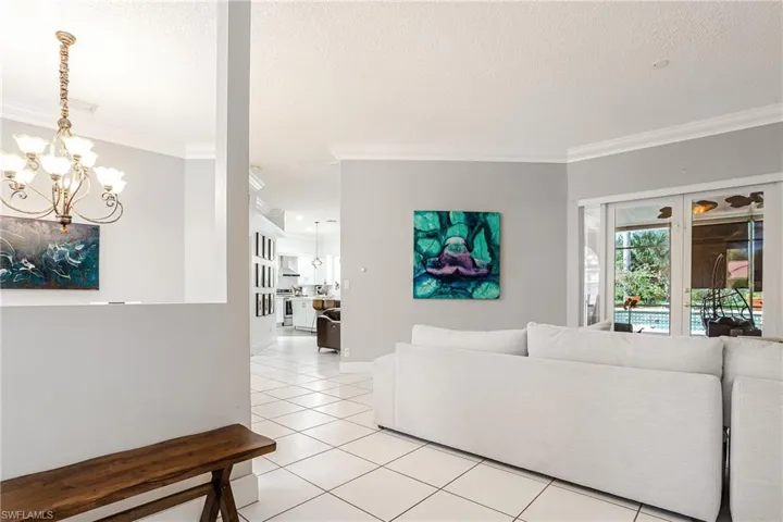 Living area with a chandelier, ornamental molding, light tile patterned floors, and a textured ceiling