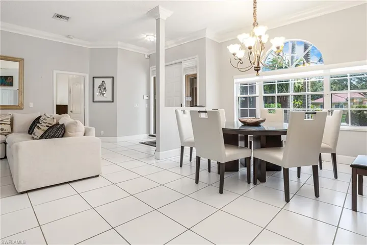 Dining space with light tile patterned floors, ornamental molding, and a chandelier