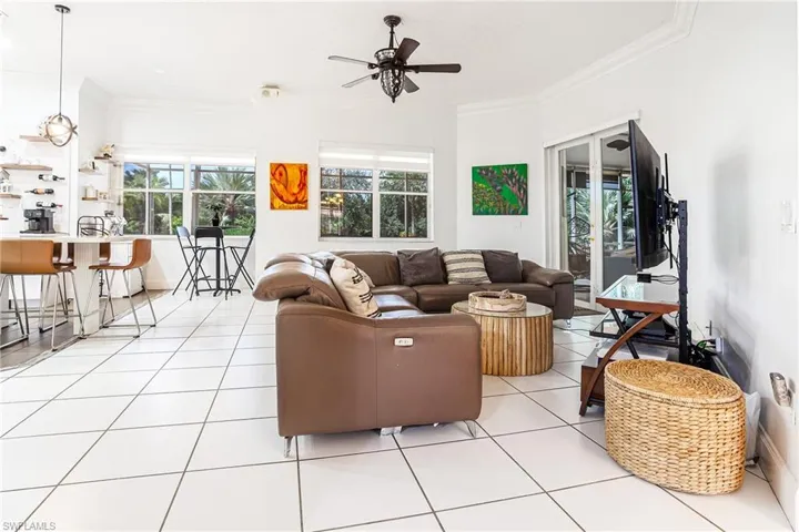 Living area with crown molding, healthy amount of natural light, light tile patterned floors, and ceiling fan