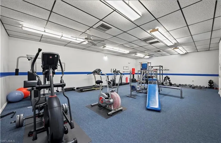 Workout area with ceiling fan and a paneled ceiling