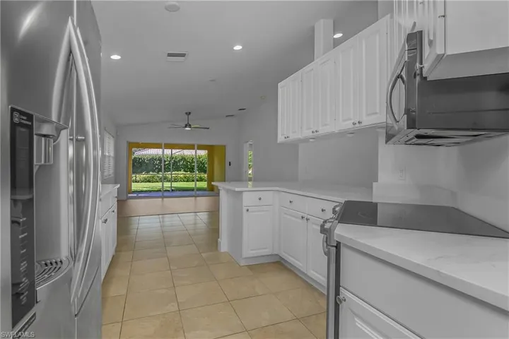 Kitchen featuring white shaker-style cabinetry, solid-surface countertops, tile flooring, recessed lighting, and stainless steel appliances