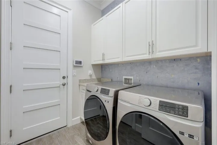 Washroom with washing machine and clothes dryer, cabinet space, and wood finished floors