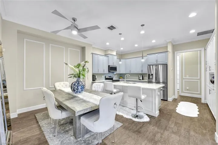 Dining area with dark wood-style flooring, ornamental molding, and visible vents