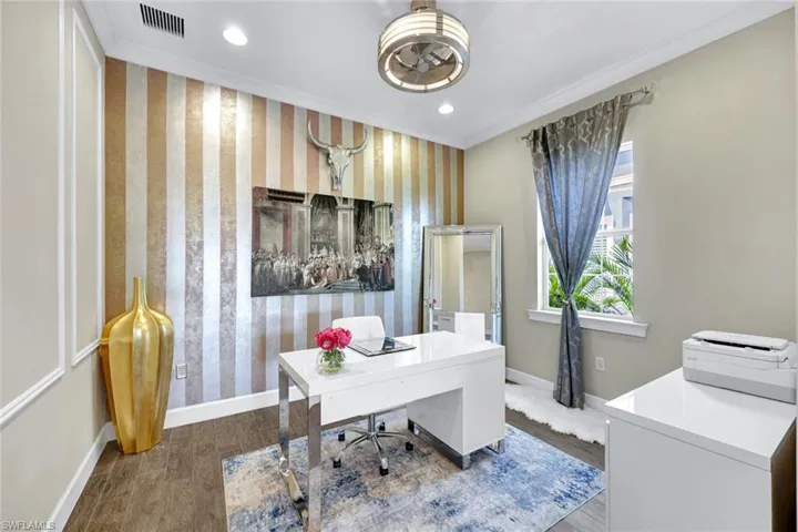 Office space featuring wallpapered walls, baseboards, and visible vents