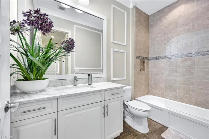 Full guest bath with visible vents, toilet, wood finished floors, vanity, and  shower combination
