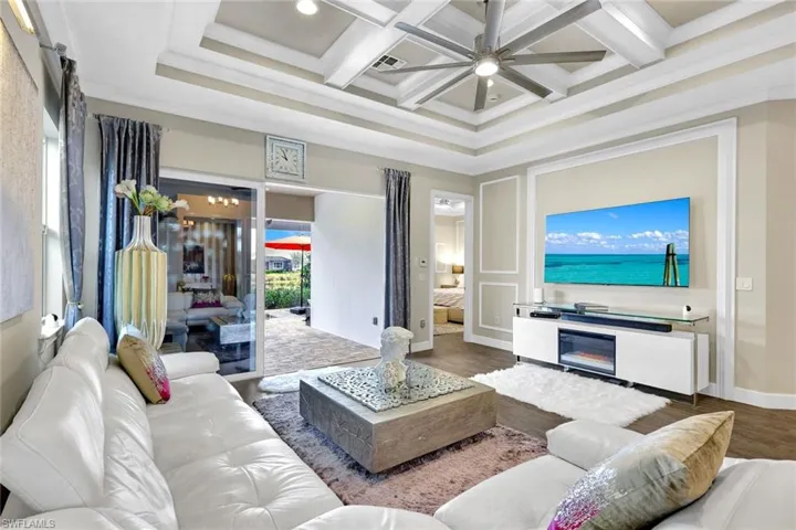 Living room featuring visible vents, crown molding, a ceiling fan, beam ceiling, and coffered ceiling