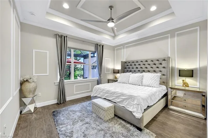 Master Bedroom featuring baseboards, wood finished floors, ornamental molding, and a raised ceiling
