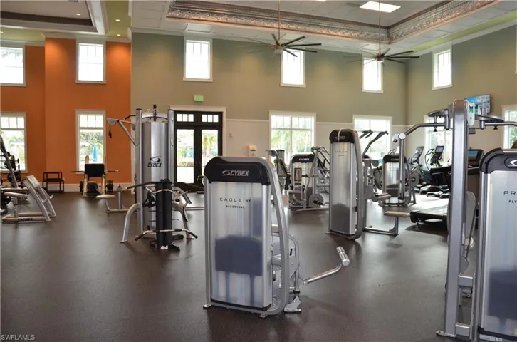 Fitness Center workout area featuring crown molding, ceiling fan, a tray ceiling, and a high ceiling
