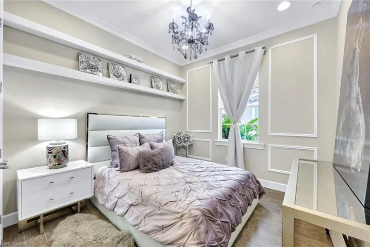 Guest Bedroom with an inviting chandelier, crown molding, baseboards, and wood finished floors