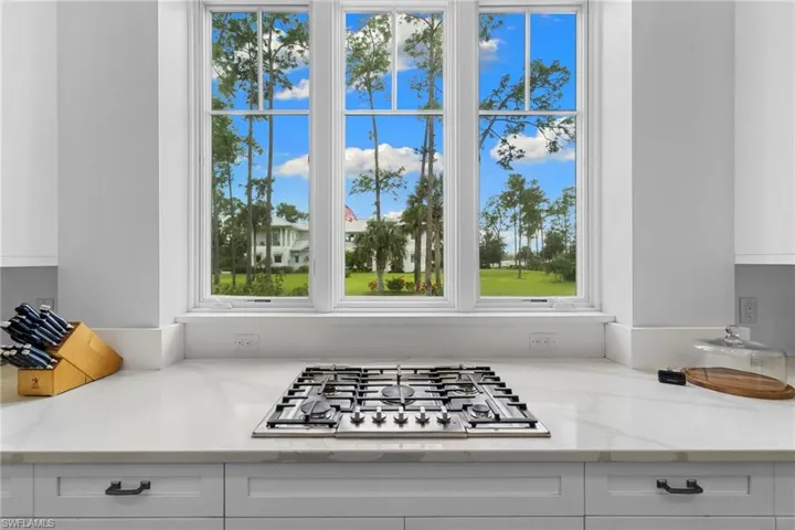Kitchen view of white cabinets, light stone counters, and stainless steel gas cooktop