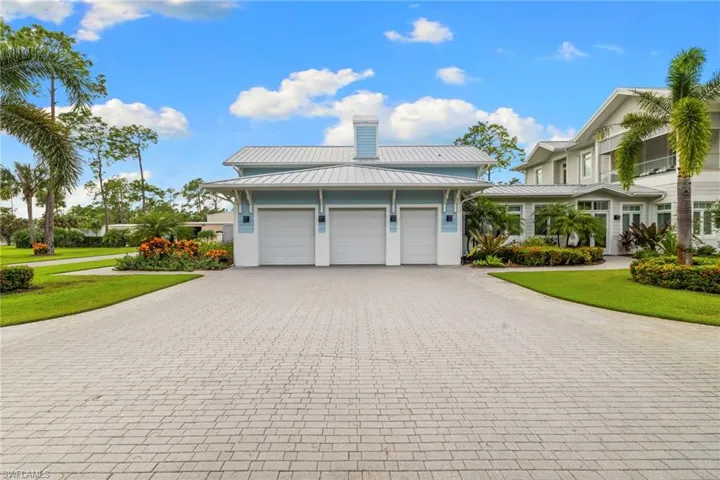 View of home's exterior featuring a metal roof, decorative driveway, a standing seam roof, an attached garage, and a lawn