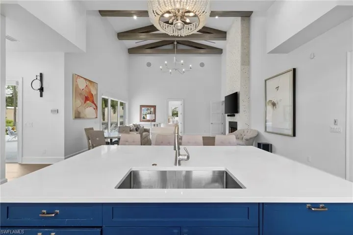 Kitchen with blue cabinets, high vaulted ceiling, beam ceiling, a center island with sink, and open floor plan