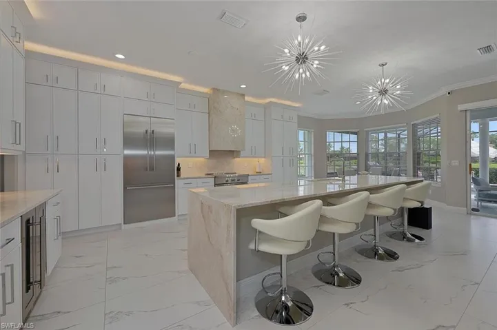 Kitchen Featuring NEW Thermador Appliances with Stainless Steel Finishes, Light Marble Style Floors and 2 Chandeliers