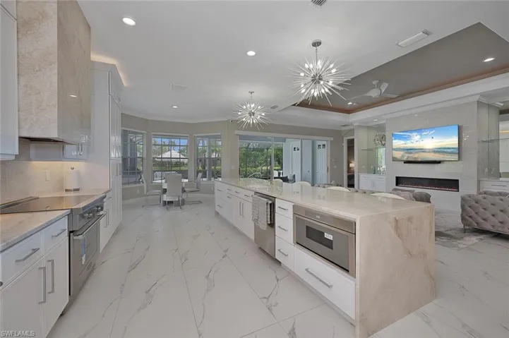 with Appliances with Stainless Steel Finishes, Crown Molding, Recessed Lighting,  Fireplace, and Light Marble Style Flooring