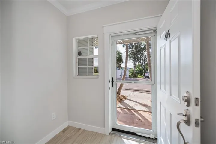 Doorway to outside featuring ornamental molding and wood finished floors