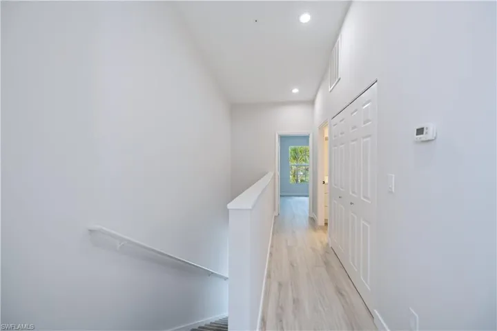 Hallway featuring an upstairs landing, recessed lighting, and light wood-style floors
