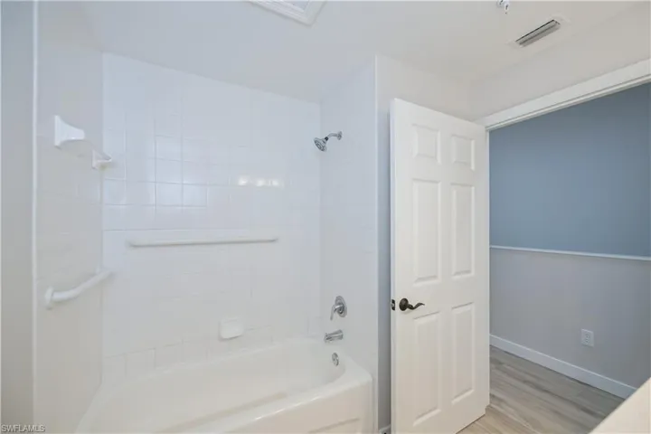 Bathroom with shower / bathtub combination and light wood finished floors