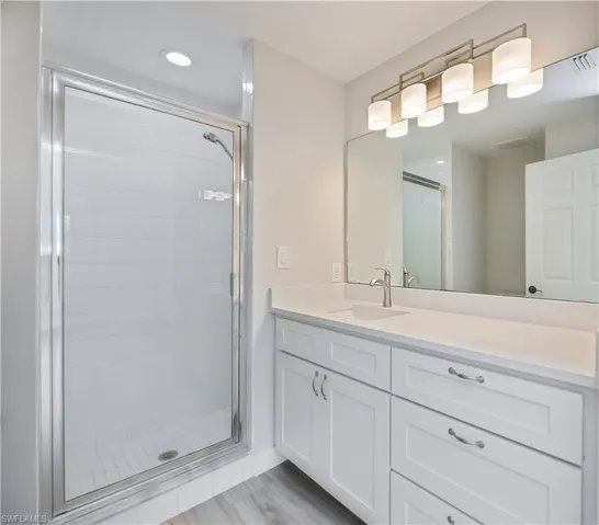 Bathroom featuring a shower stall, vanity, and recessed lighting