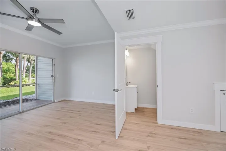 Empty room with crown molding, light wood finished floors, and a ceiling fan