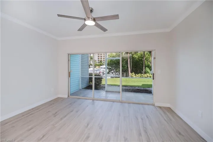 Empty room featuring light wood-style flooring, ornamental molding, and ceiling fan