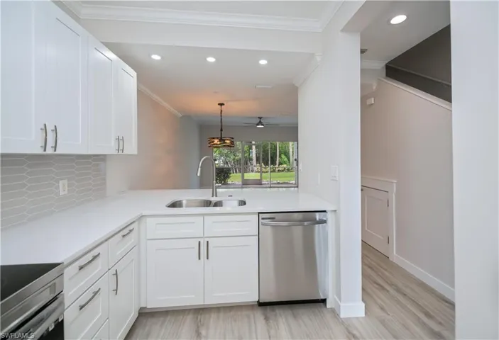 Kitchen with stainless steel appliances, ornamental molding, white cabinetry, tasteful backsplash, and pendant lighting