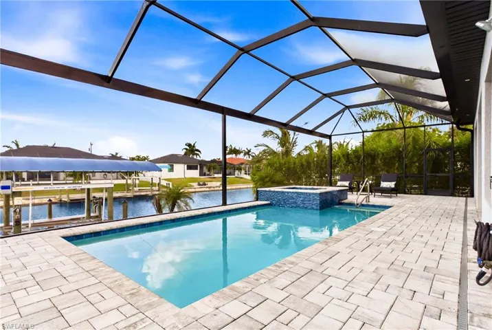 Screened lanai featuring a swimming pool, integrated spa with mosaic tile, and paver decking