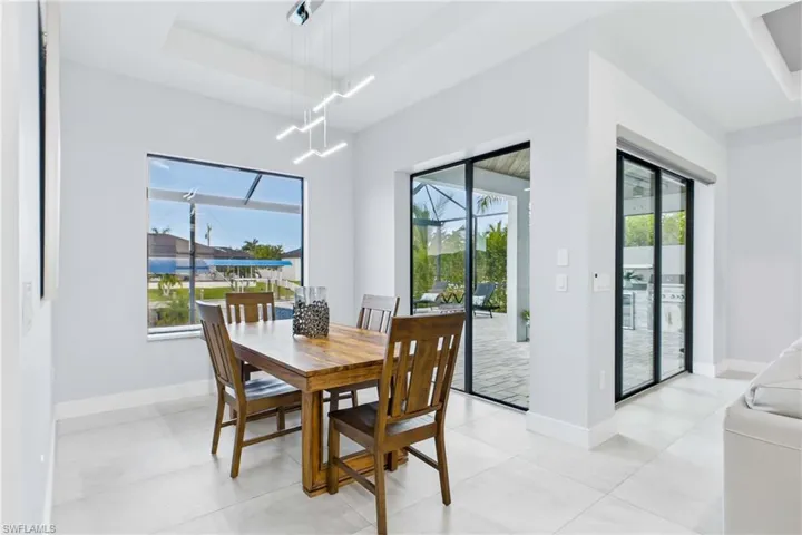 Open concept interior featuring light tile flooring, a large window with exterior water views, and a contemporary linear chandelier