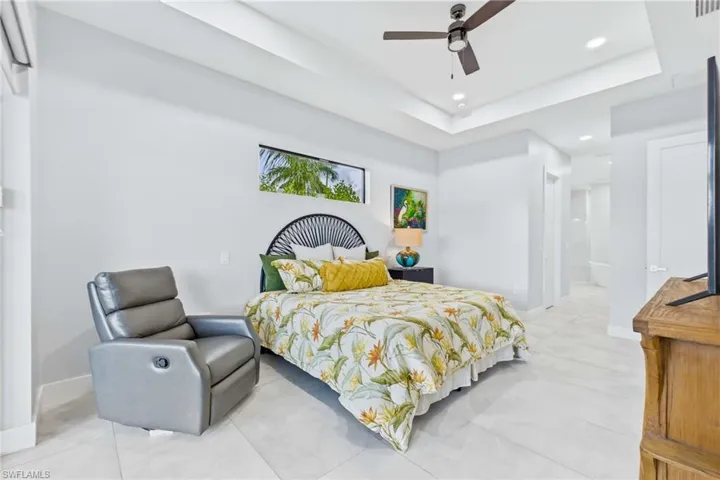 Bedroom featuring tray ceiling with recessed lighting and ceiling fan