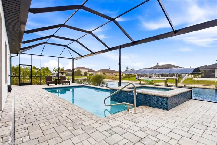 Screened lanai featuring a swimming pool and integrated spa with blue mosaic tile