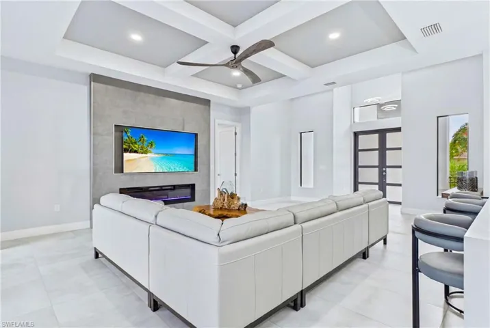 Spacious open-concept living area featuring a tray ceiling with recessed lighting and a ceiling fan