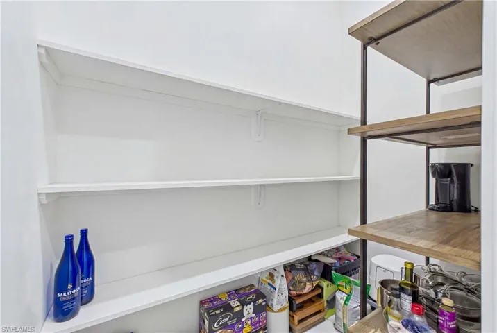 Built-in pantry shelving featuring painted white wood shelves and freestanding industrial-style shelving with wood-finish surfaces and a dark metal frame