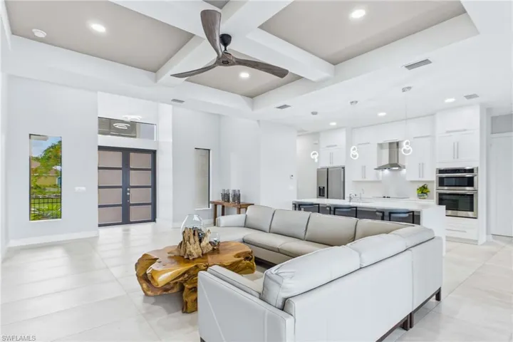 Open-concept living area featuring a coffered ceiling with a modern ceiling fan, recessed lighting, and large format tile flooring