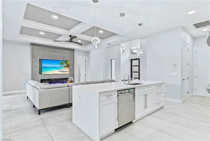 Open-concept living area featuring a kitchen island with white cabinetry and stainless steel appliances