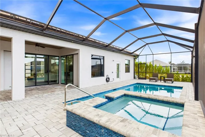 Screened-in outdoor area featuring a swimming pool, integrated spa with mosaic tile detailing, and a spacious paver patio