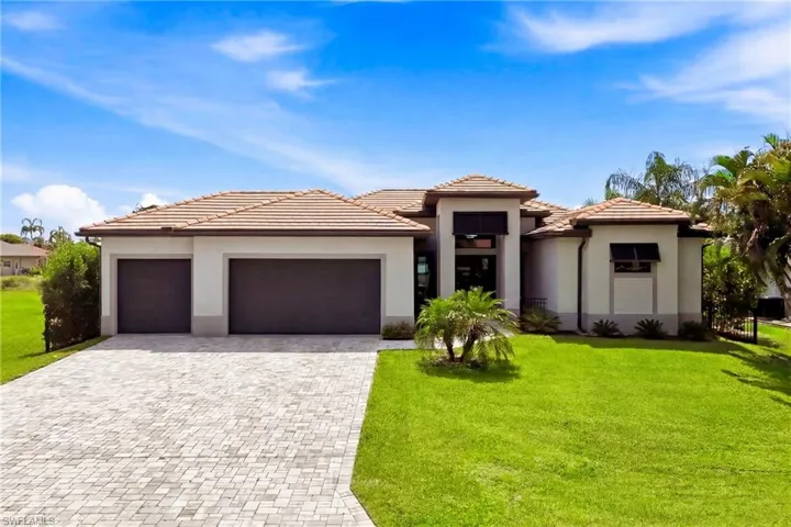 Contemporary exterior featuring a paver driveway, two-car garage, tile roofing, and a manicured lawn