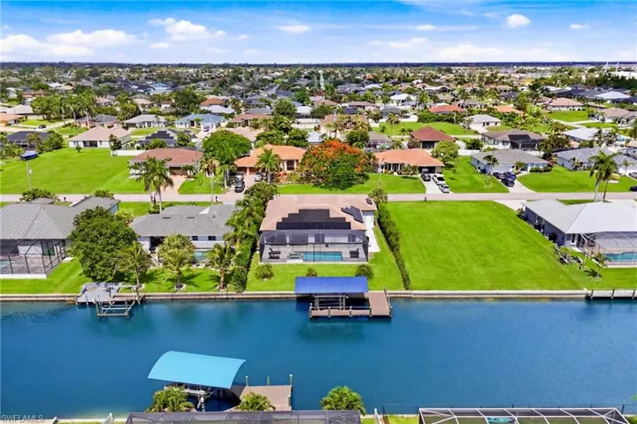 Waterfront parcel featuring a boat dock, boat lift with blue canopy, and manicured lawn