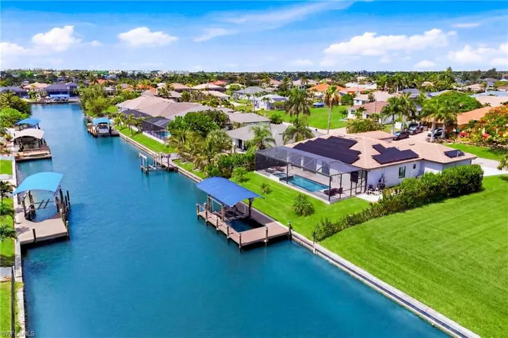 Waterfront property featuring a private boat dock with canopy, screened-in swimming pool, and solar panel installation