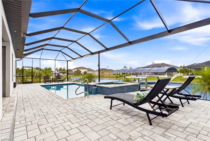 Screened lanai featuring a swimming pool, integrated spa with mosaic tile detailing, and a spacious paver patio