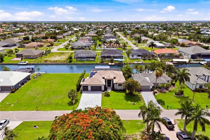 Canal-front property featuring a well-maintained lawn and mature landscaping