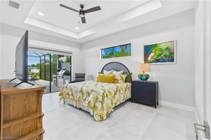 White tile flooring throughout the room features a tray ceiling with recessed lighting and a ceiling fan
