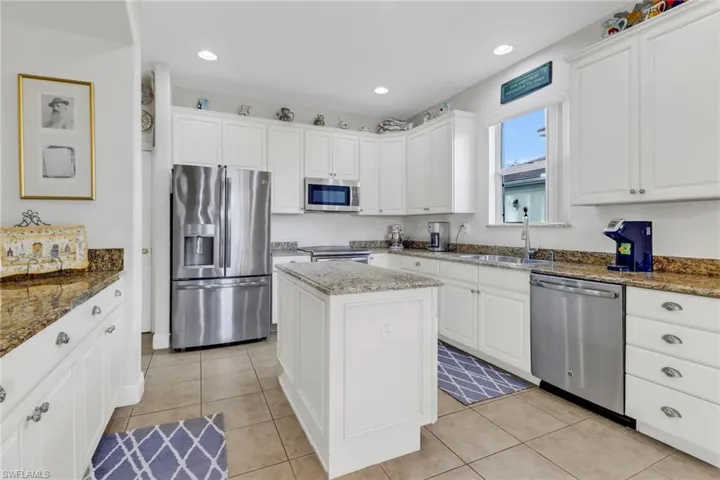 Kitchen with dark stone countertops, sink, a kitchen island, and stainless steel appliances