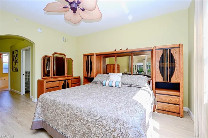 Bedroom with arched walkways, baseboards, and light wood-style floors