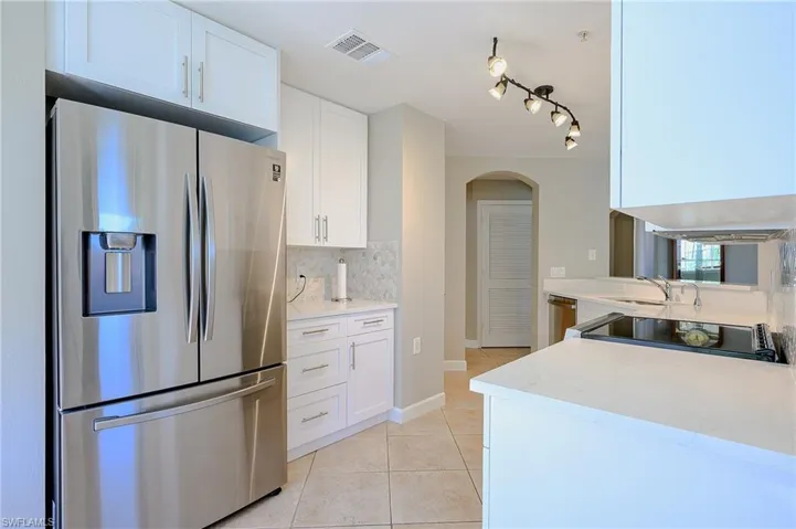 Kitchen featuring arched walkways, decorative backsplash, light tile patterned floors, appliances with stainless steel finishes, and visible vents