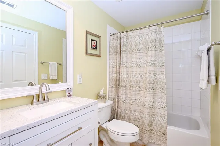 Bathroom with shower / bathtub combination with curtain, visible vents, toilet, and vanity
