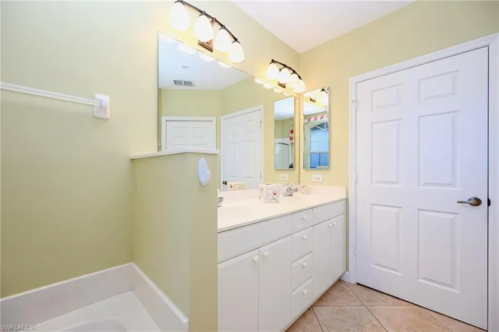 Bathroom featuring tile patterned floors, a sink, visible vents, and double vanity