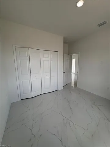 Unfurnished bedroom with baseboards, a closet, and marble finish flooring