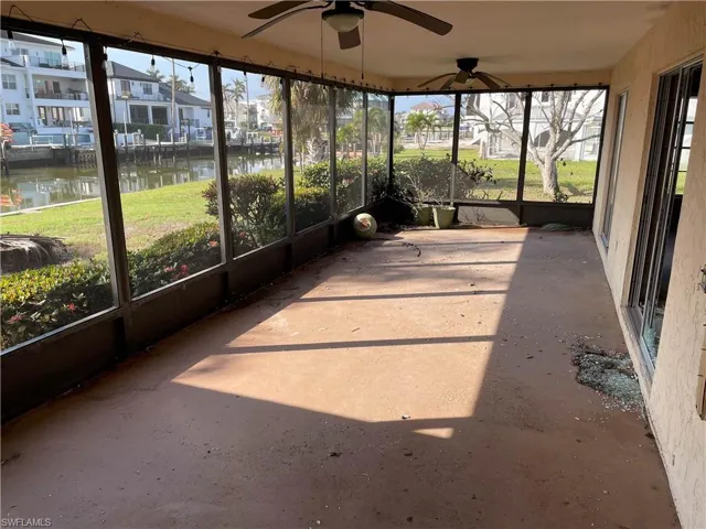 Unfurnished sunroom featuring a water view, plenty of natural light, and ceiling fan