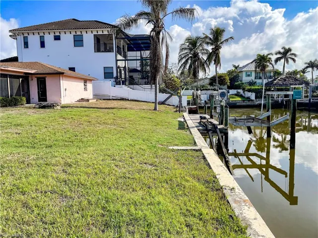 Dock area with a lanai, a water view, and a lawn