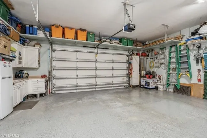Garage with a garage door opener and white refrigerator