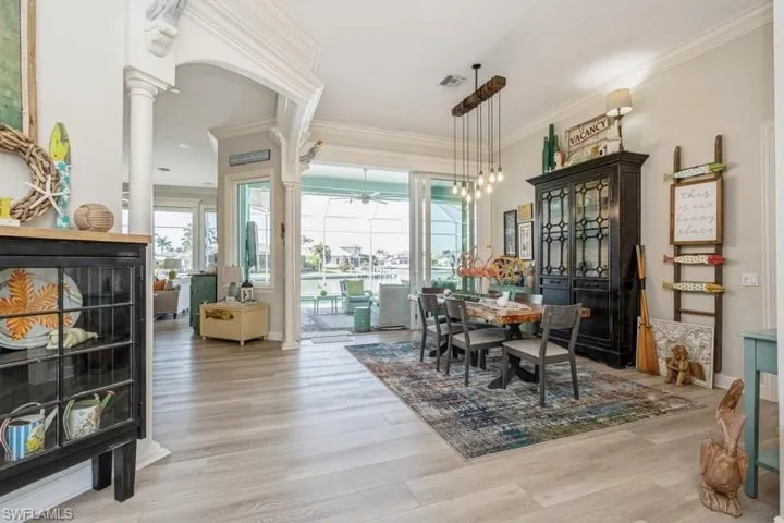 Dining room featuring crown molding, decorative columns, and light wood-type flooring